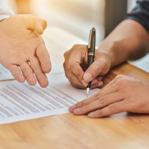 Close up hand holding pen sign contract on document